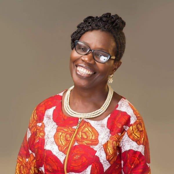 Smiling woman in a red patterned top and pearl necklace