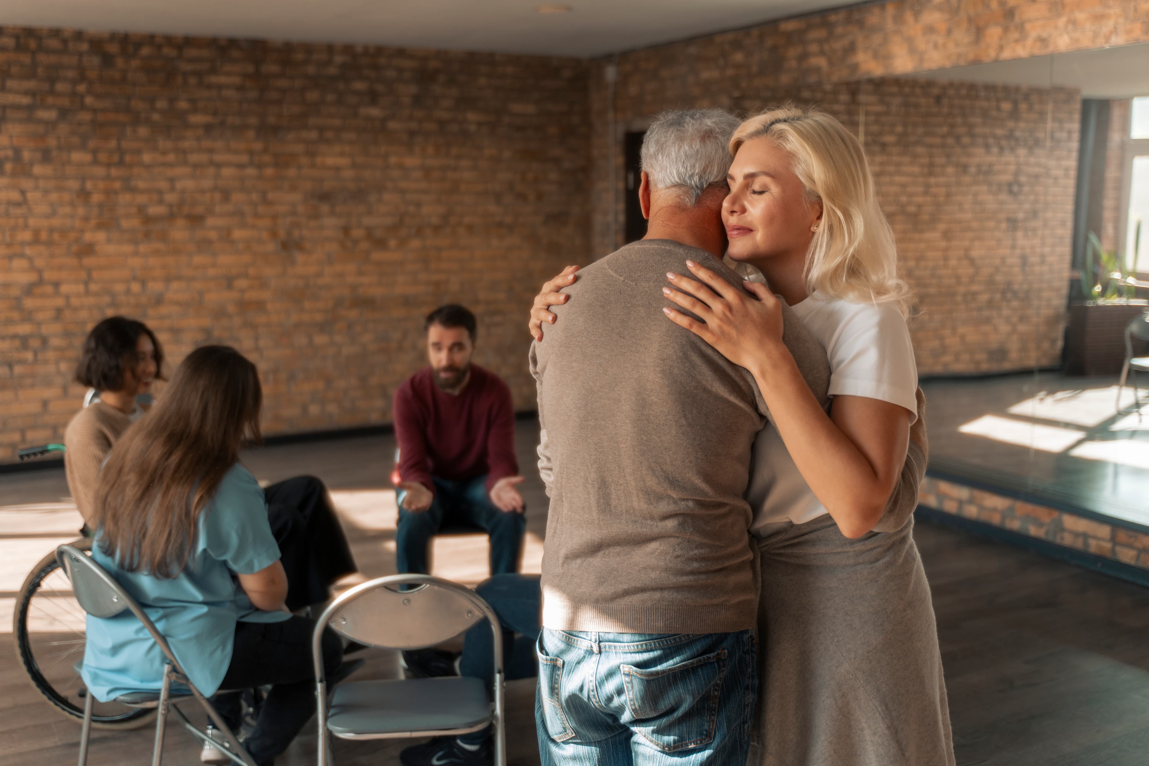 Participants in a group session, two embracing in the foreground
